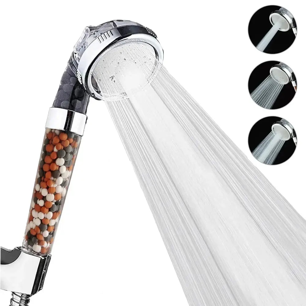 Handheld showerhead with transparent handle showing multicolored mineral beads, emitting a strong water spray, against a white background from Home Essentials-6&