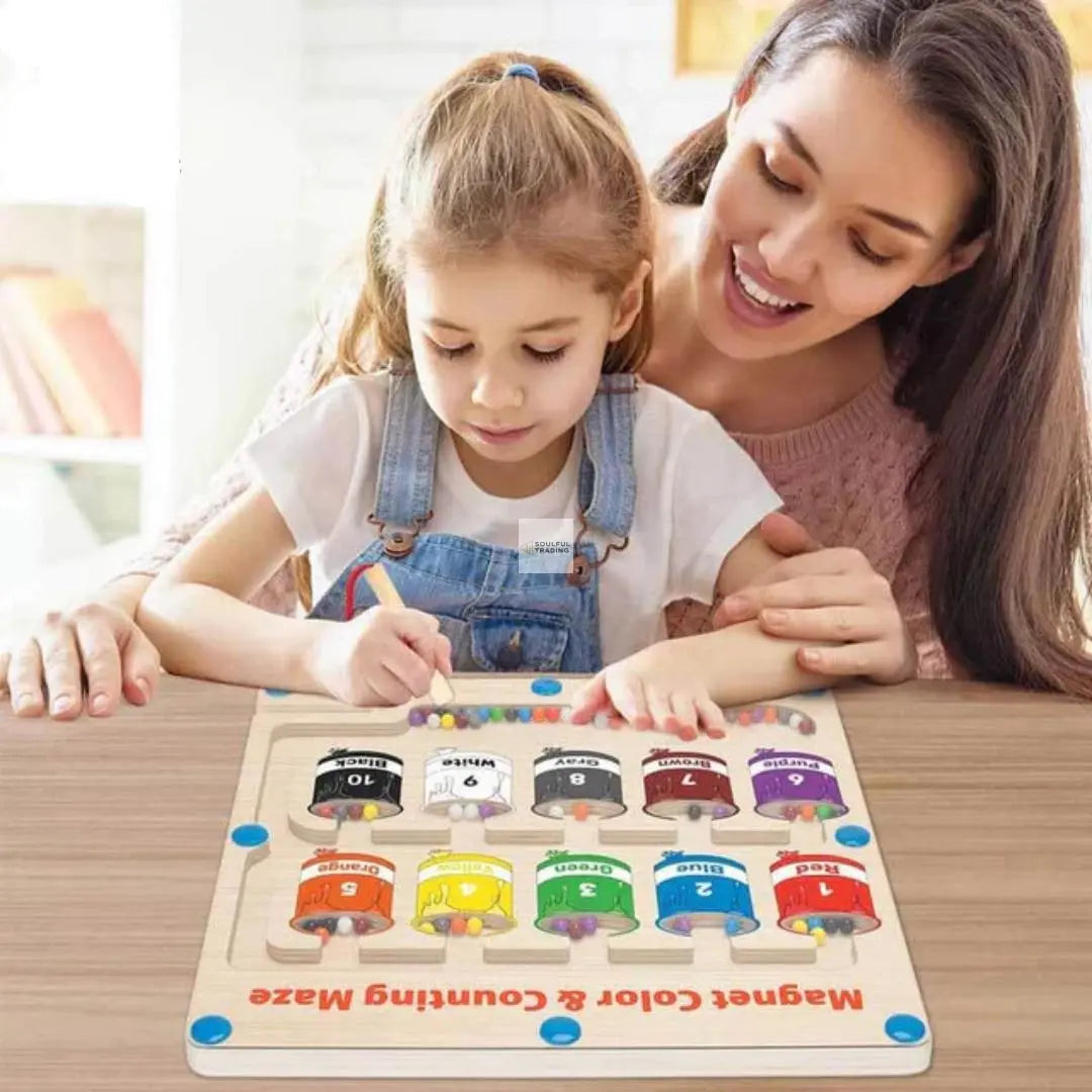 A woman and a young girl engage with a colorful Soulful Trading Montessori magnetic labyrinth toy on a table, both smiling as the child places a puzzle piece.
