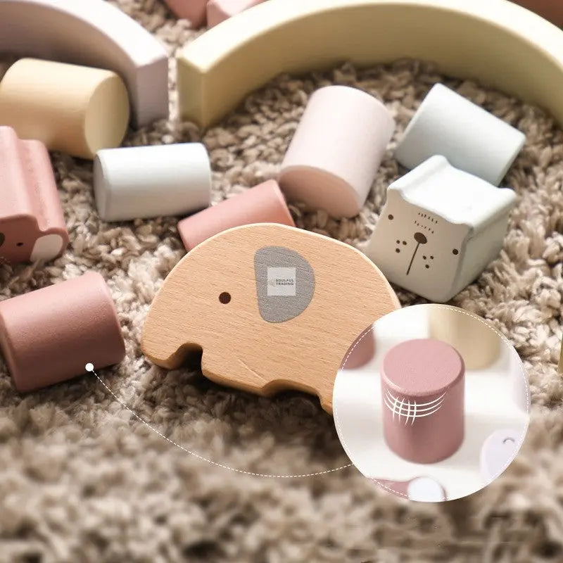 Soulful Trading Montessori Educational Wooden Elephant Balance Toy surrounded by various pastel-colored blocks on a textured rug, with emphasis on a circular pink block.
