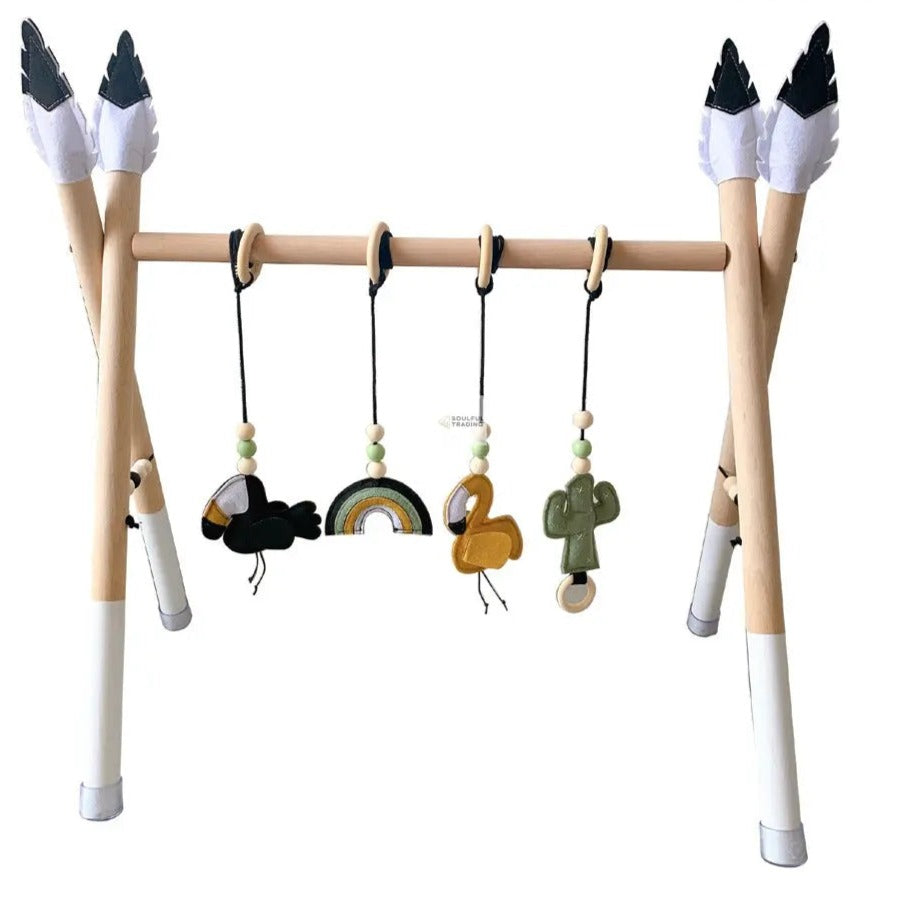A Soulful Trading Montessori Education Nordic Wooden Exercise Machine with dangling toys including a mini rainbow, beads, a duck, and a cactus in Montessori-inspired design, supported by legs with capped black-and-white tips resembling bird feet.
