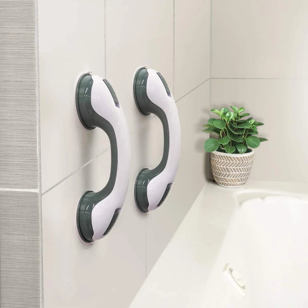 Two Soulful Trading Adjustable Shower Standing Handles with non-slip grip installed on a light gray tiled bathroom wall next to a bathtub, with a potted plant in the background.