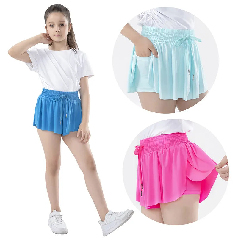 Young girl in a white t-shirt and blue Soulful Trading Girls Butterfly Shorts, posing with a hand on her hip. Insets show details of similar shorts in teal and pink.