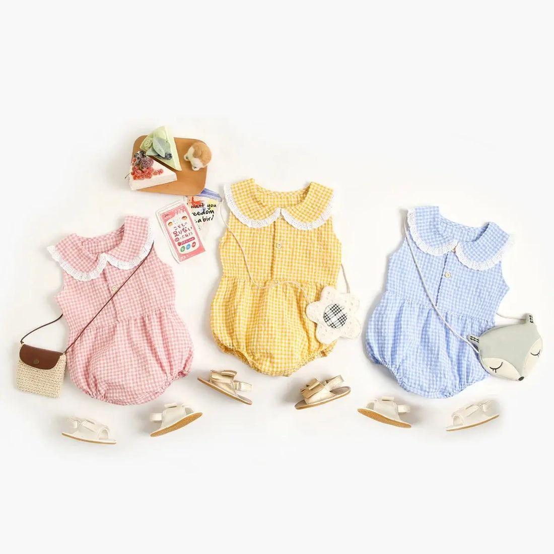 Three Spring &amp; Summer Baby Onesie outfits laid out, each with a onesie, shoes, and accessories, in pink, yellow, and blue colors by Soulful Trading.