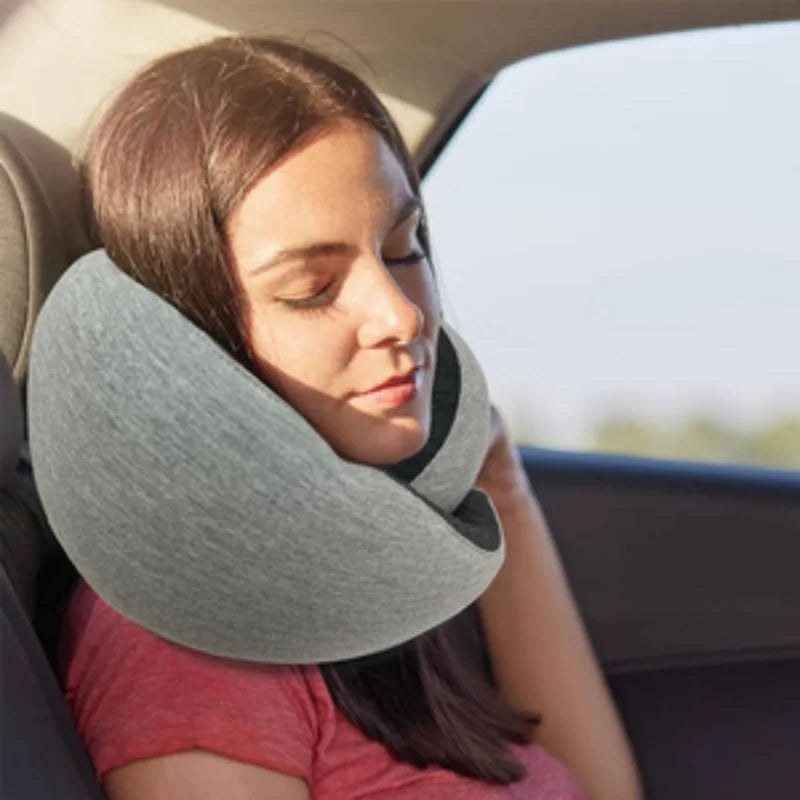 A woman sleeping in a car, using a gray Vertebra Cervical Neck Pillow from Soulful Trading for support.